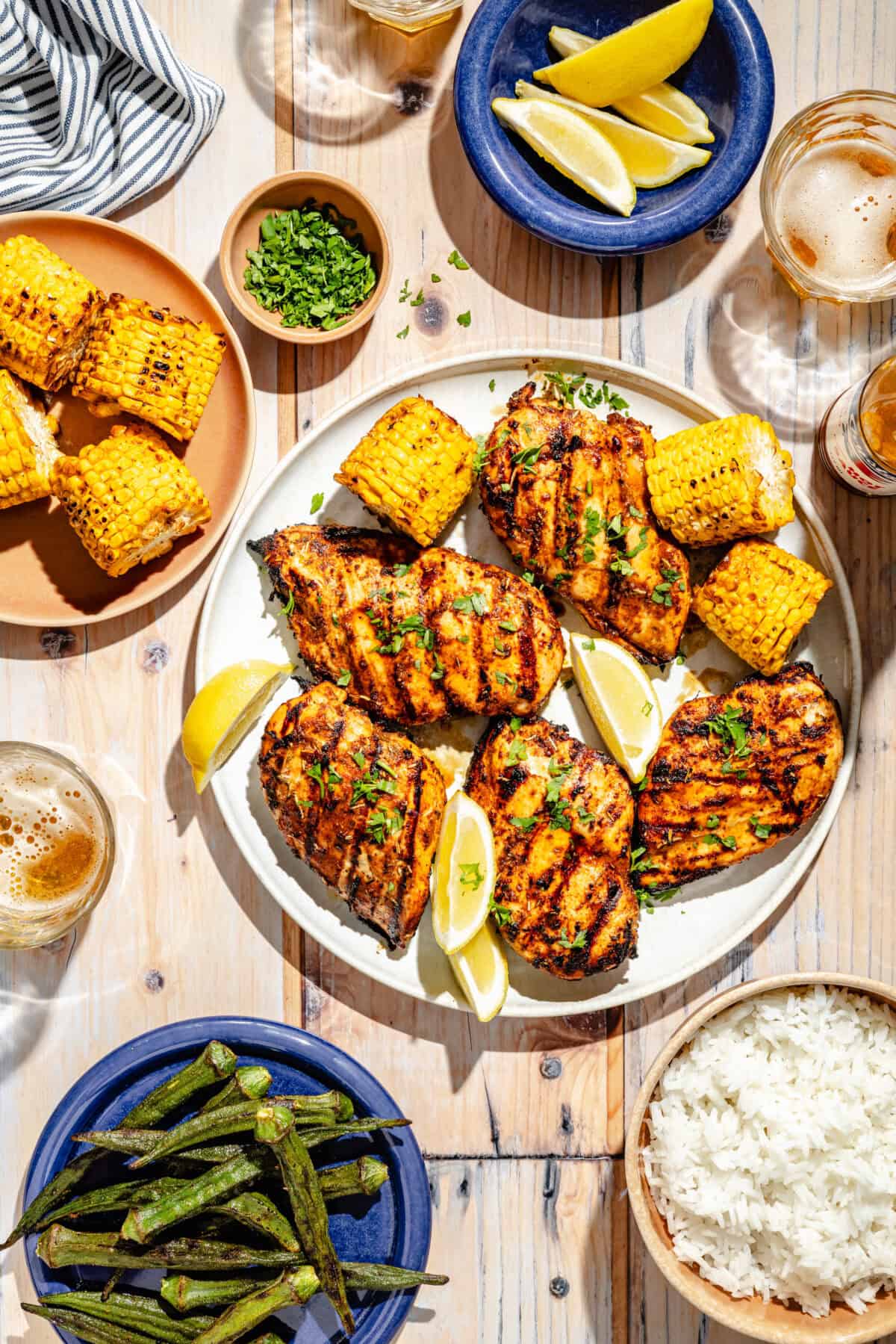 Grilled Cajun Chicken on plate with side plates of rice and okra.