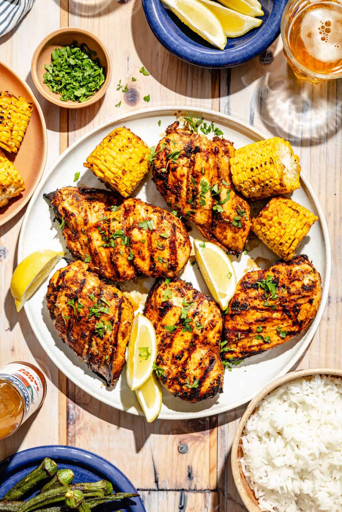 Grilled Cajun Chicken on plate with corn and sliced lemons.