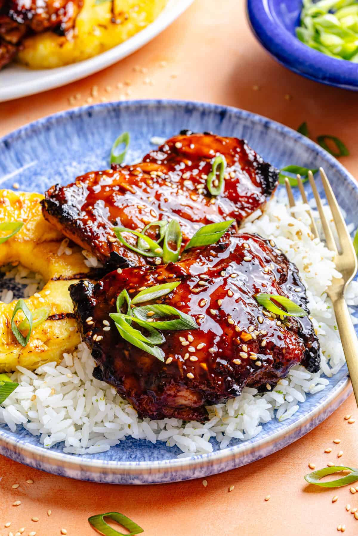 Huli Huli–Inspired Chicken in bowl over rice with sliced pineapple.