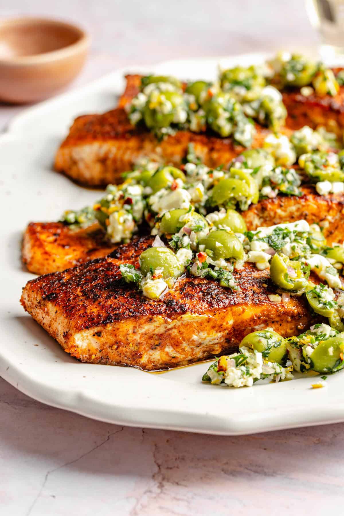 Close up of Pan-Seared Salmon with Castelvetrano Olive and Feta Salsa on platter.