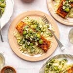 Pan-Seared Salmon with Castelvetrano Olive and Feta Salsa plated on variety of pink and white plates.