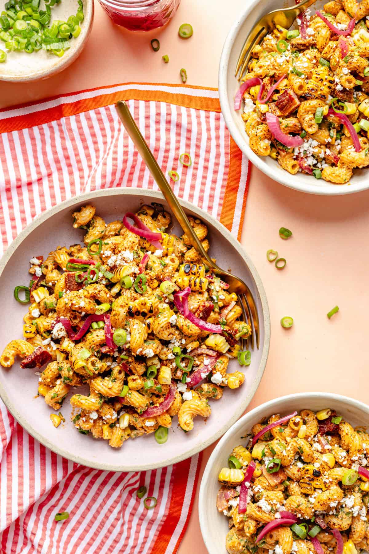 Smoky Chipotle Bacon Pasta Salad in bowls on pink surface.