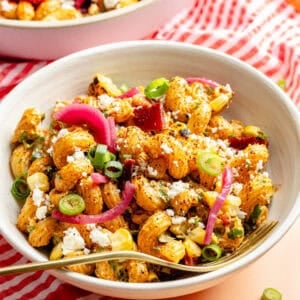 Smokey Chipotle Bacon Pasta Salad in white bowl on pink backdrop.