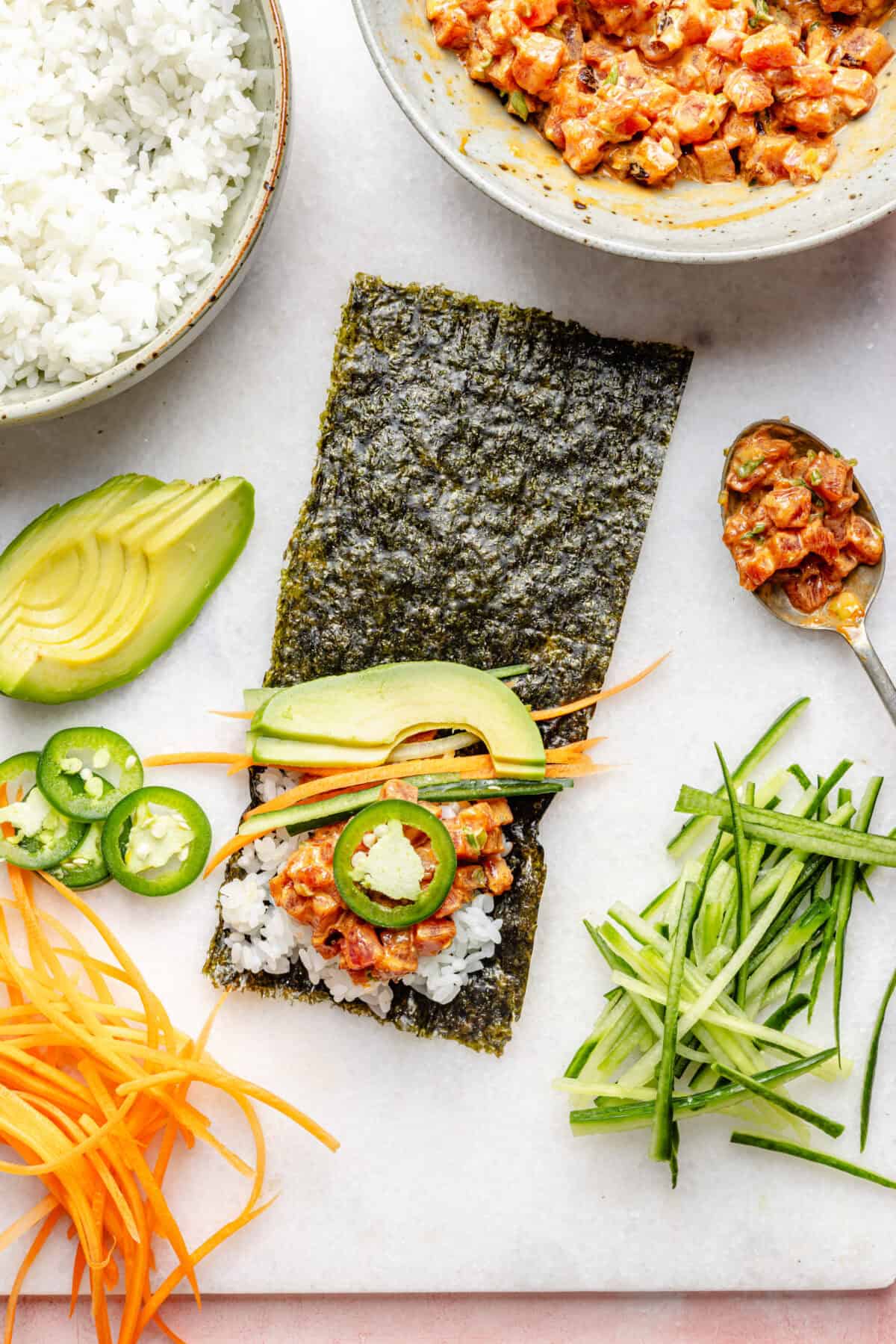 Spicy Tuna Handroll getting assembled on a white surface.