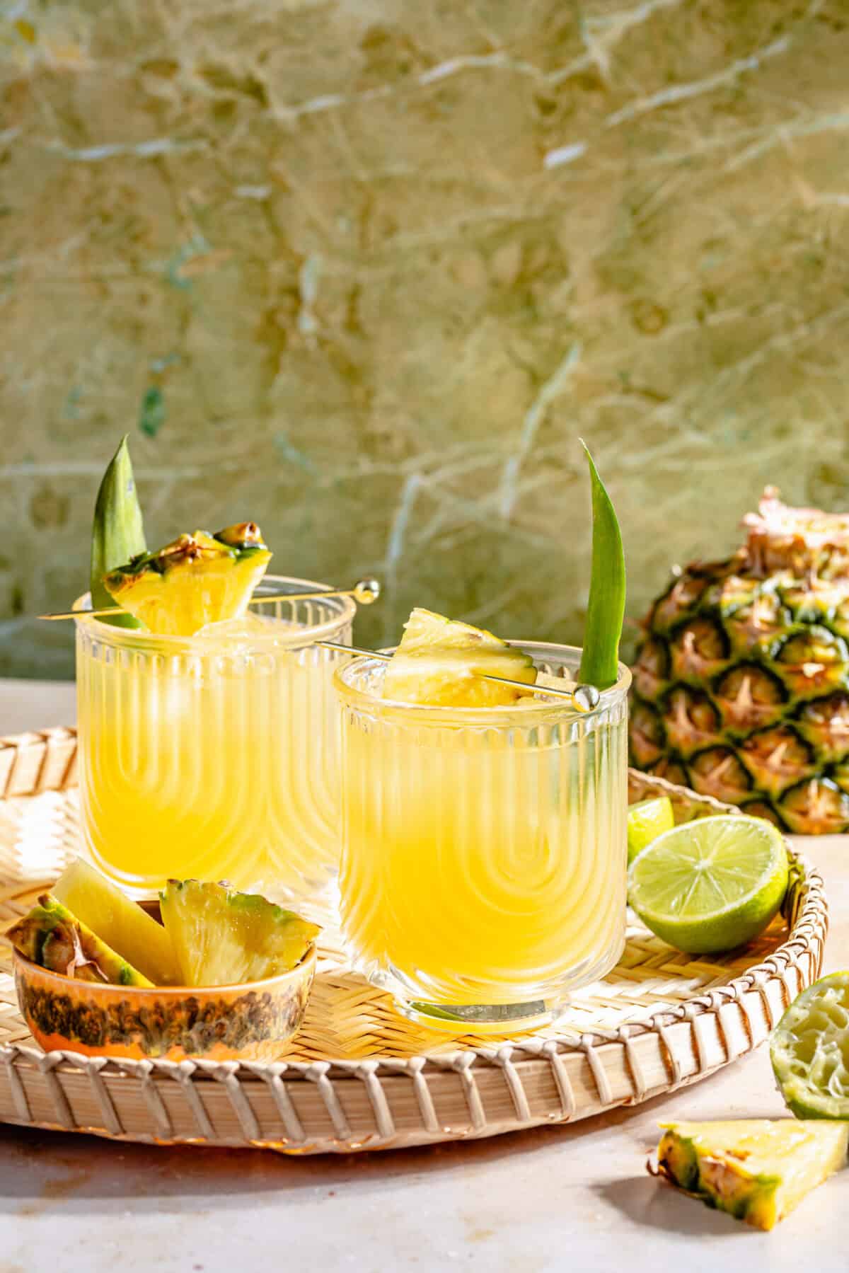 The Kauai Margarita IN TWO GLASSES ON WOVEN TRAY WITH GREEN BACKDROP