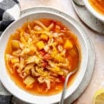 Detox Cabbage Soup in white bowl with spoon.