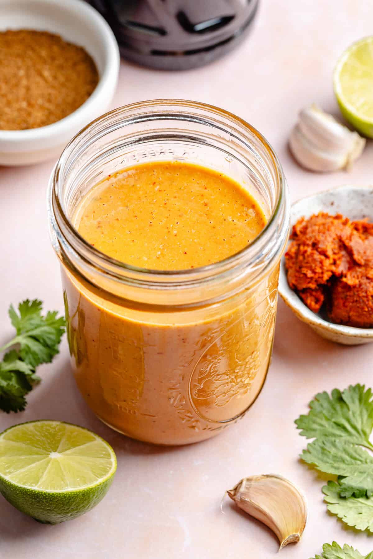 Curry sauce in glass jar with other ingredients around it.
