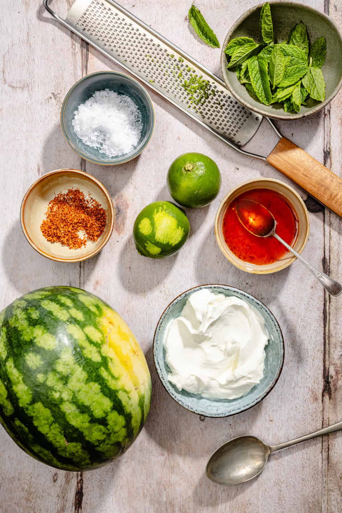 Ingredients scatter on counter for Chili Lime Watermelon with Labneh and Hot Honey.