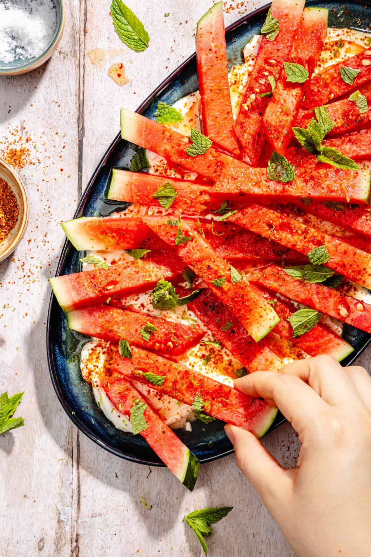 Hand grabbing slice of watermelon off of platter.