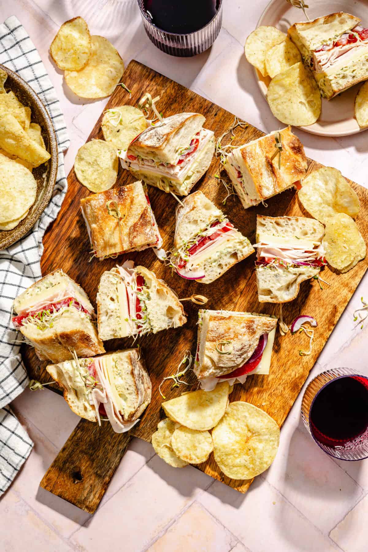 Turkey and Havarti Party Sandwiches with Dill-Pickle Mayo sliced and on wooden tray.