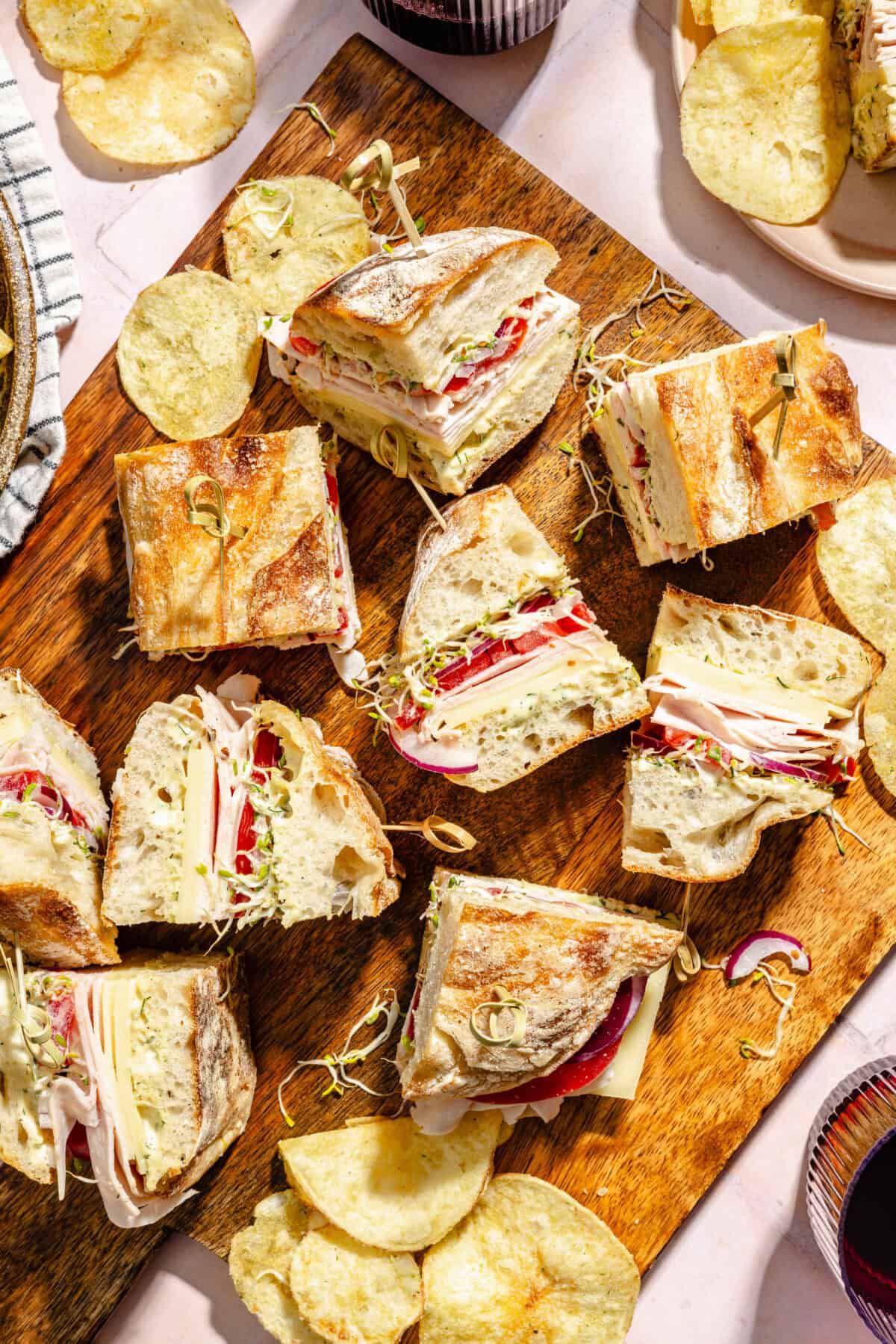 Turkey and Havarti Party Sandwiches with Dill-Pickle Mayo sliced and on a wooden serving board.