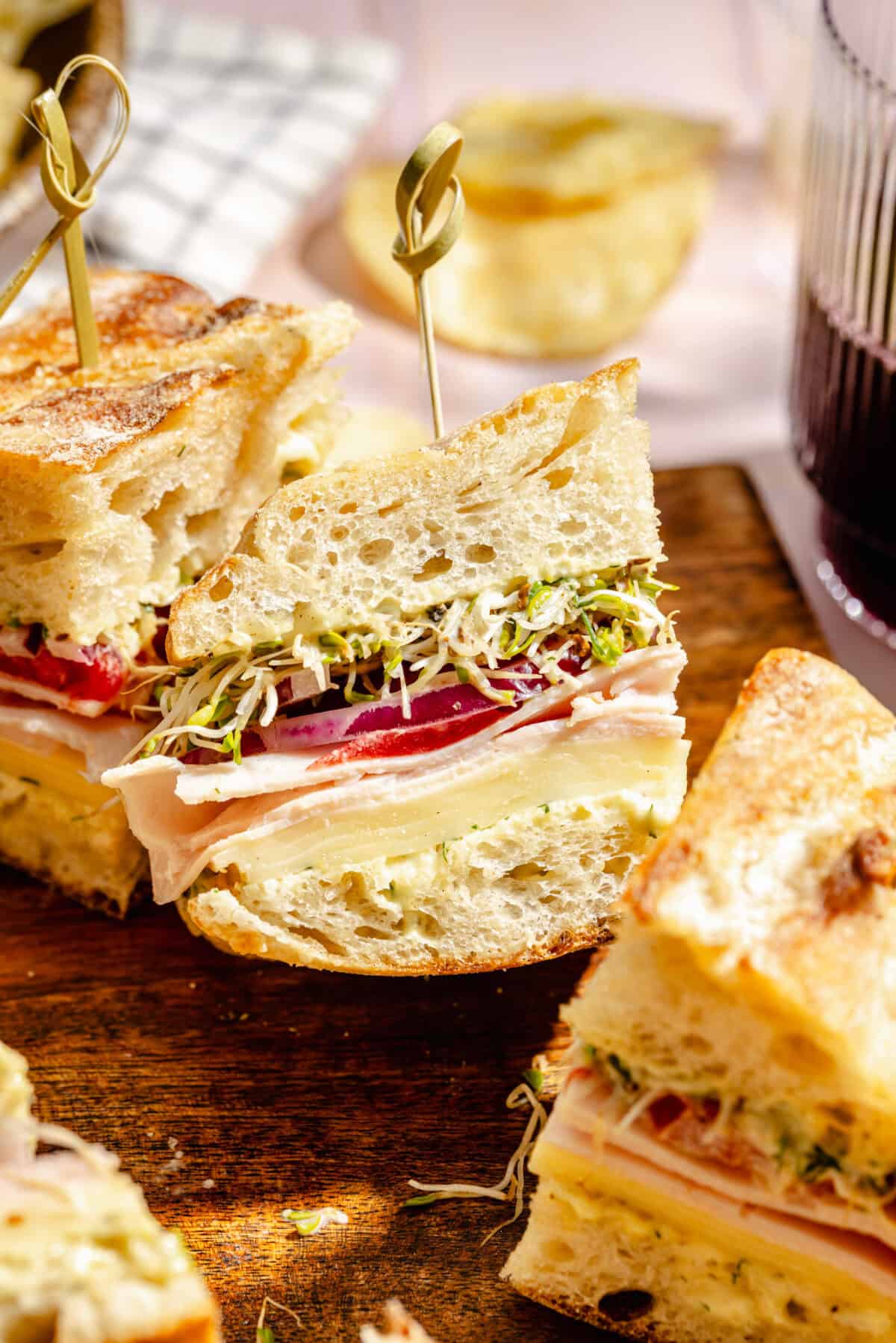 Turkey and Havarti Party Sandwiches with Dill-Pickle Mayo sliced and on wooden tray.