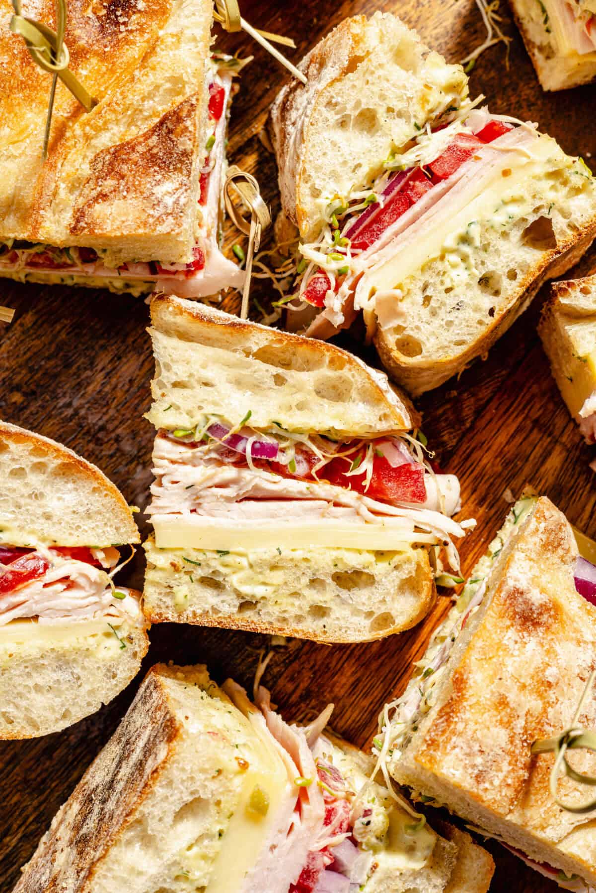 Turkey and Havarti Party Sandwiches with Dill-Pickle Mayo sliced on wooden cutting board.