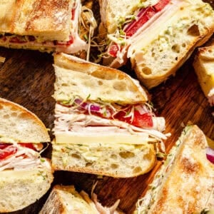 Turkey and Havarti Party Sandwiches with Dill-Pickle Mayo sliced on wooden cutting board.