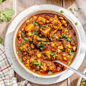 a large bowl of cowboy stew made with beef, potatoes, beans, tomatoes, and corn