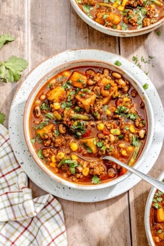 a large bowl of cowboy stew made with beef, potatoes, beans, tomatoes, and corn