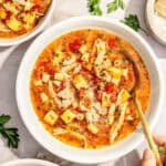 a large bowl of spicy sicilian-style soup with shredded chicken, potatoes, and pasta